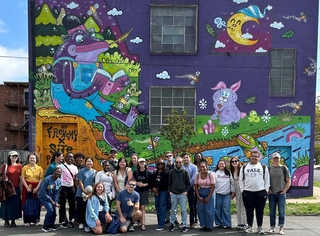 group photo of students in front of mural